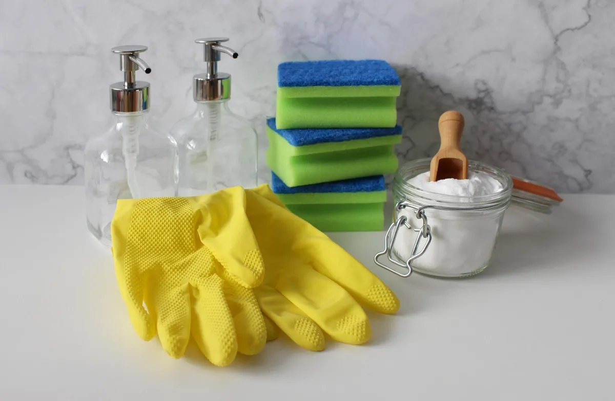 Yellow rubber gloves, sponges and soap dispensers on a countertop